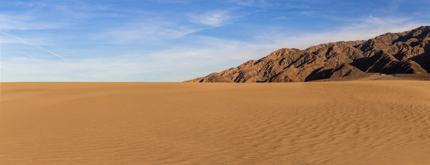 Sand dunes in a desert landscape in Death Valley California.  The vast barren land is dry and arid due to droughts result of global warming and climate change.