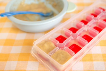 Preparing baby food, homemade. Healthy smashed banana mixed with breast milk preparing to be made as an ice cube in ice cube tray. Healthy food kids concept. Selective focus. 