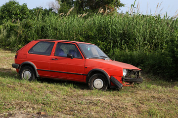 An old abandoned car rusts by the road