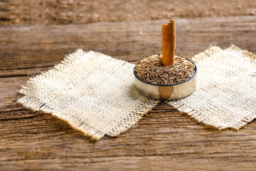 heap of dried cumin in bowl, on wooden background