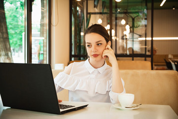 girl in cafe at lunch works behind a laptop