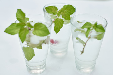 Summer hot fresh drink with mint in glass on white green grey background