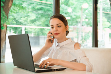 girl in cafe at lunch works behind a laptop