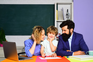 Little schoolboy ready to study. Parenting education. Couple helping his son to make homework. First day at school. September 1. Kid from elementary school with parents in school. Elementary student.