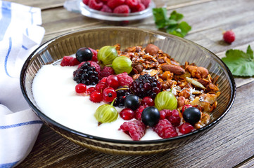 Yogurt, granola, fresh berries in a bowl on a wooden table. Delicious and healthy breakfast. Proper nutrition. Dietary menu.