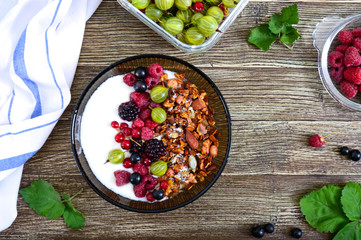 Yogurt, granola, fresh berries in a bowl on a wooden table. Delicious and healthy breakfast. Proper nutrition. Dietary menu. The top view, flat lay