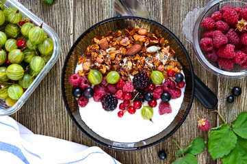 Yogurt, granola, fresh berries in a bowl on a wooden table. Delicious and healthy breakfast. Proper nutrition. Dietary menu. The top view, flat lay