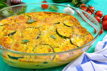 Zucchini, cheese, eggs, cream and green casserole in a transparent glass form on a bright background. Tasty healthy dish.