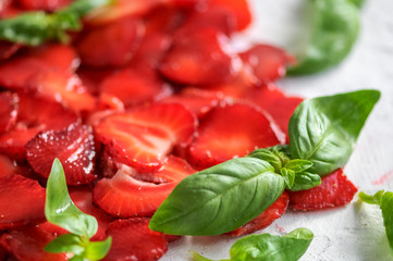 plate of strawberries with sliced ​​basil leaves on white background