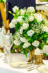 Valentines party dinner table setting with tableware and silverware and glasses set and Candlestick and flower in restaurant.