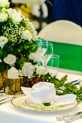 Christmas party dinner table setting with tableware and silverware and glasses set and Candlestick and flower in restaurant.