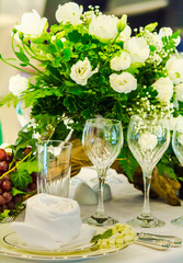 Christmas party dinner table setting with tableware and silverware and glasses set and Candlestick and flower in restaurant.