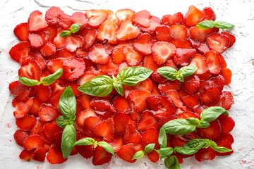 plate of strawberries with sliced ​​basil leaves on white background