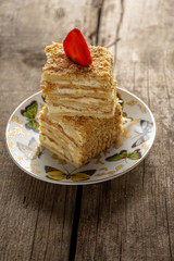 Napoleon cake dessert decorated with strawberries on a beautiful plate on an old wooden background