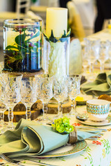 Wedding party dinner table setting with tableware and silverware and glasses set and Candlestick and flower in restaurant.