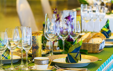 Wedding party dinner table setting with tableware and silverware and glasses set and Candlestick and flower in restaurant.