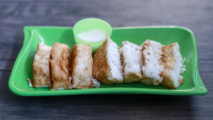 Pancong cake or kue pancong and sugar on wood background. Street food in Jakarta, Indonesia. 