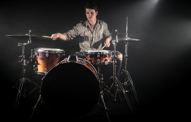 Fototapeta na wymiar Professional drummer playing on drum set on stage on the black background