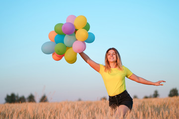 Happiness, enjoy the life, birthday party, bright moment, summer fun, creativeness. Young girl with big bunch of colorful balloons standing in sunset meadow