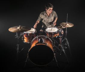 Fototapeta na wymiar Professional drummer playing on drum set on stage on the black background