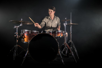 Fototapeta premium Professional drummer playing on drum set on stage on the black background