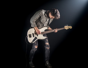 the musician plays bass guitar, on a black background with a beam of light