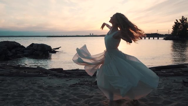 ballerina dancing and spinning on the sea at sunset