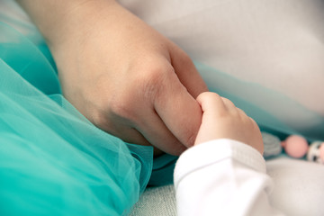 The child holds the mother by the hand, squeezing her fingers with his tiny hand.