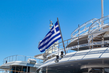 Greek flag on a yacht, cruise to islands. Clear blue sky background
