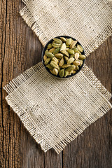 Cardamom seeds in a bowl on a wooden background