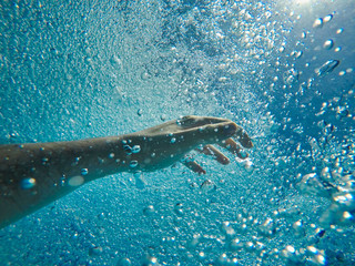 hand underwater submerged between bubbles