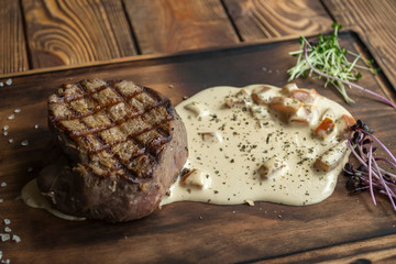 Grilled meat with spices and sauce on a wooden table.	