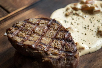 Grilled meat with spices and sauce on a wooden table.	