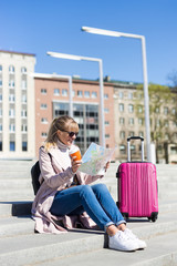 summer vacation, tourism and travel concept - young woman with map and suitcase in the city