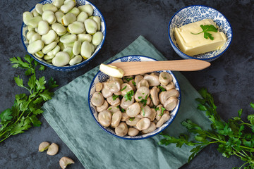 Boiled broad beans served in a bowl with butter and parsley