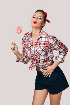 beautiful pin-up woman with pink lollipop on gray background