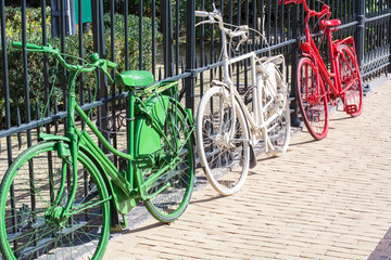 Three colorful bikes - green, white and red - are on the dutch street in the sunlight