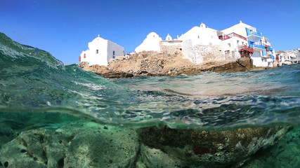 Sea level and underwater photo of iconic landmark chapel of Paraportiani in famous landmark little Venice with crystal clear emerald sea, Mykonos island, Cyclades, Greece