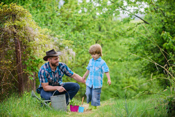 Naklejka na ściany i meble Take care of plants. Boy and father in nature with watering can. Gardening tools. Dad teaching little son care plants. Little helper in garden. Make planet greener. Planting flowers. Growing plants