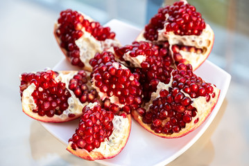 The fresh red tasty opened pomegranate on a white dish
