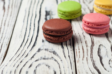 Row of colorful and tasty french cookies macaroons on old white wooden boards