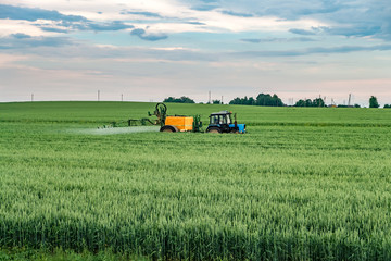 Farmer spraying wheat field with tractor sprayer at spring season