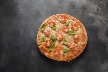 Homemade Italian Neapolitan pizza Margherita with melted mozzarella cheese and tomatoes garnished with fresh basil