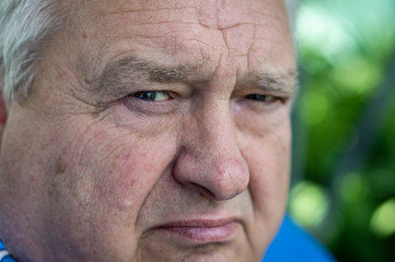 Angry old grandfather looks into the camera lens