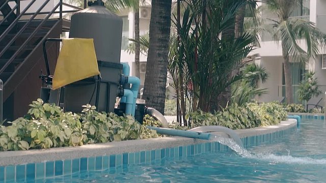 modern powerful pump fills large hotel swimming pool with fresh water at tropical resort slow motion