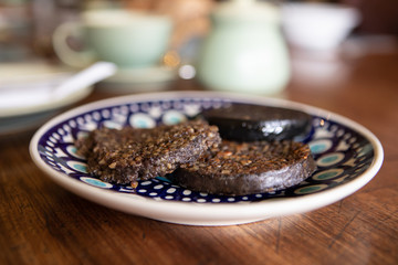 traditional scottish Haggis are served for breakfast on a hand painted plate with a blurred background