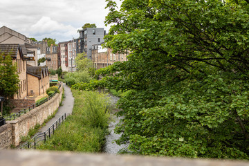 Fototapeta na wymiar view down a bridge in Stockbridge, Edinburgh to the Water of Leith, with lush trees and a pathway