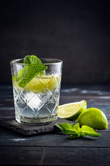 Vodka with water and ice in a glass Cup - alcoholic cocktail with lime and mint