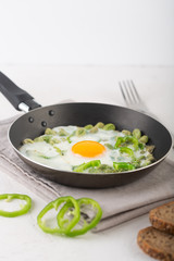 Green shakshuka. Fried eggs with fresh pepper, beans on a gray background, rustic style