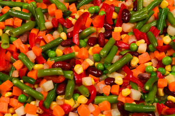 Sliced vegetables, corn, beans, peas, carrots, sweet peppers background.